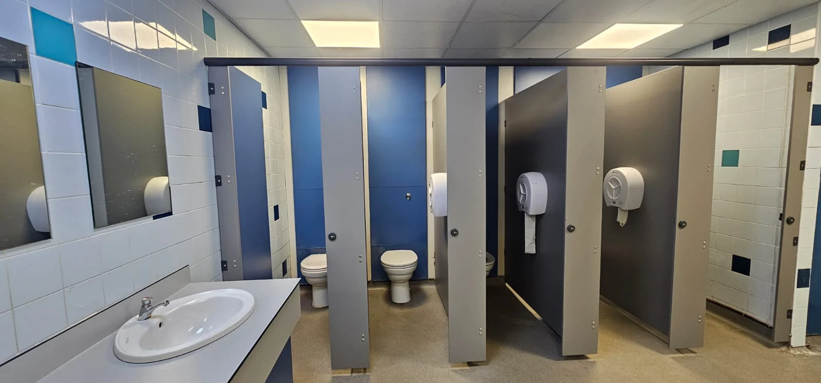 Washroom with blue cubicles and washbasins