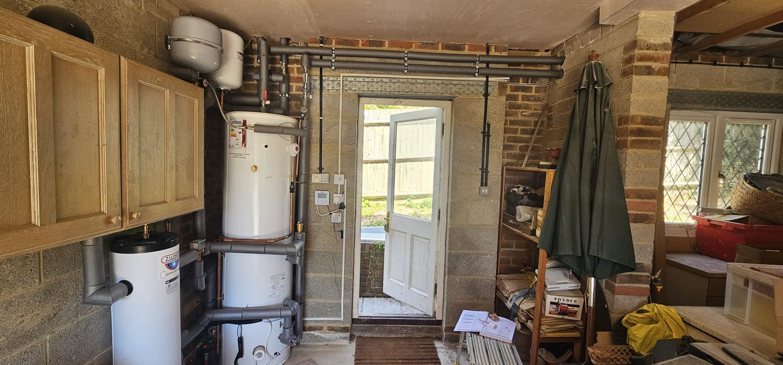 Utility room with hot water cylinder, buffer vessel and insulated pipework installed along the wall